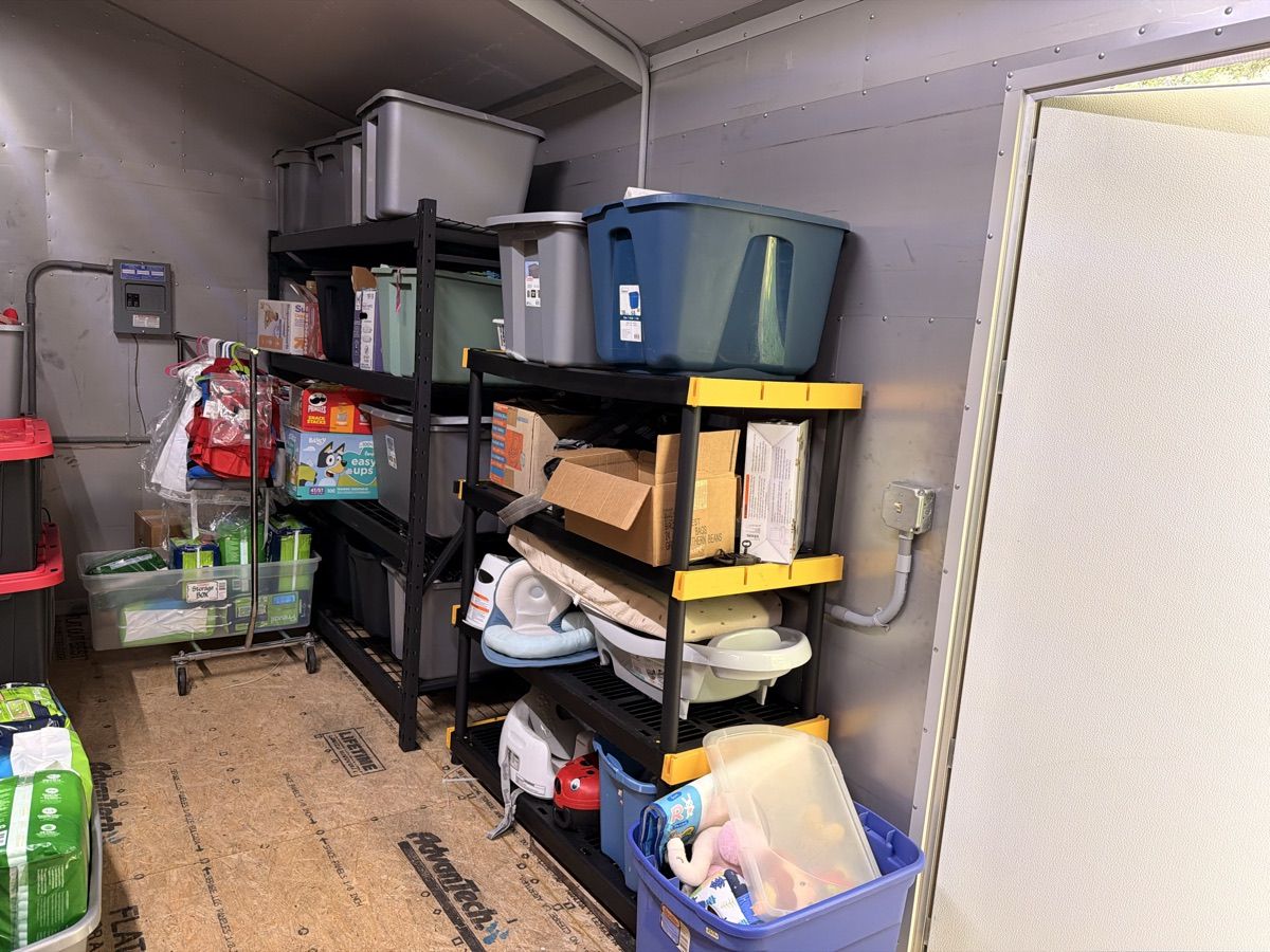Shelves of storage totes, baby bath seats, and boxed supplies just inside the warehouse door.